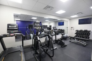 A gym with treadmills, elliptical machines, and weight benches.