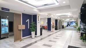 A modern hotel lobby with a reception desk, a vending machine, and a large number '1' on the wall. - Holiday Inn Express Washington DC SW - Springfield by IHG (Springfield)