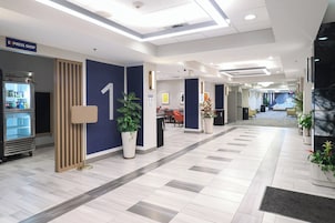 A modern hotel lobby with a reception desk, a vending machine, and a large number '1' on the wall.
