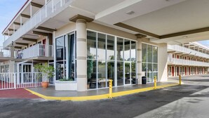 A hotel with a modern design, featuring a large glass facade, multiple balconies, and a red carpet entrance. - Rodeway Inn Clearwater - Largo (Clearwater)