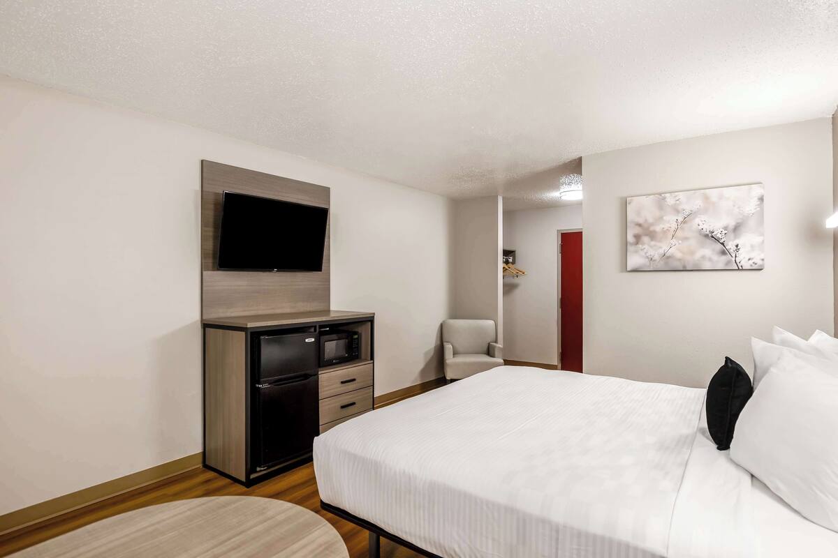 Une chambre d’hôtel équipée d’un lit, d’un bureau avec un téléviseur à écran plat, d’un four à micro-ondes et d’une chaise.