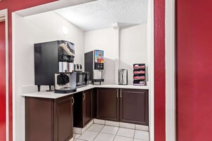Una kitchenette equipada con cafetera, microondas y dispensador de bebidas.