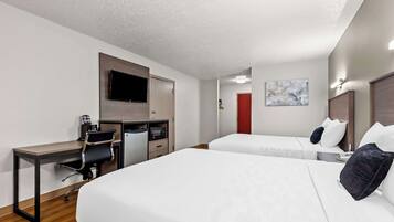 Habitación de hotel con escritorio, dos camas, televisor y puerta roja.