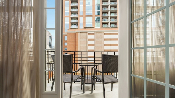 Un balcon avec deux chaises et une table, donnant sur un immeuble de grande hauteur.