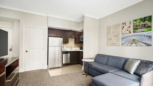 Un appartement moderne doté d’une kitchenette, d’un canapé gris et d’une petite table ronde.