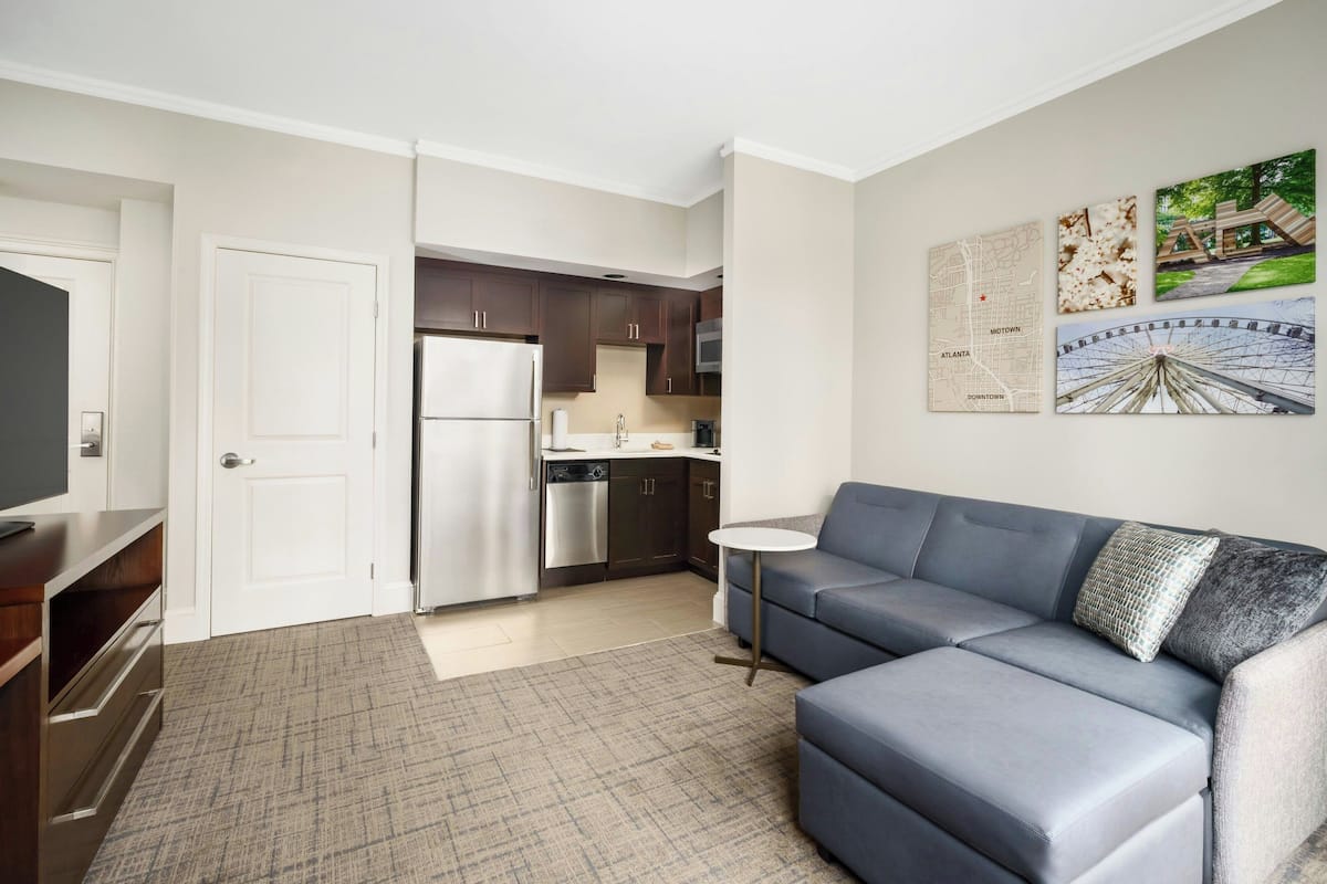 Un appartement moderne doté d’une kitchenette, d’un canapé gris et d’une petite table ronde.