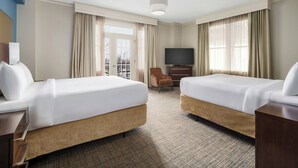 Une chambre d’hôtel avec deux lits, une télévision, un bureau et une chaise.