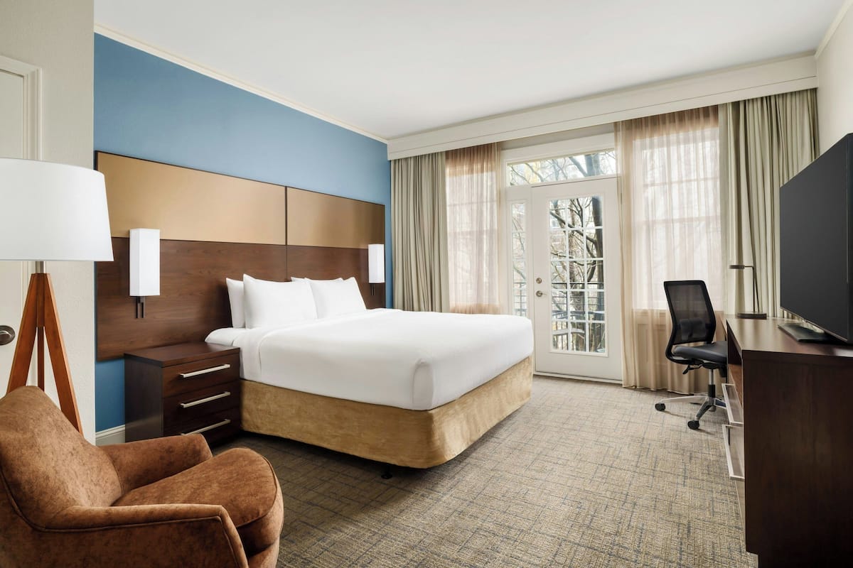 Une chambre d’hôtel avec un grand lit, un bureau avec une chaise, une lampe et un téléviseur.