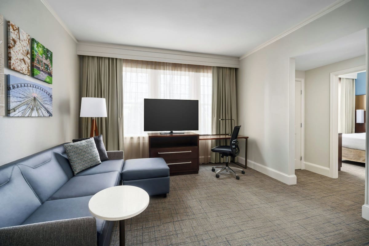 Une chambre d’hôtel avec un canapé, une télévision, un bureau et une chaise.