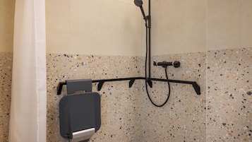 A shower area with a handheld showerhead, a handheld shower attachment, and a wall-mounted faucet.