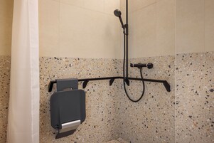 Ein Duschbereich mit Duschbrause, Handbrause und am Wand befestigtem Wasserhahn.