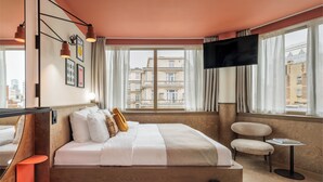 A hotel room with a large bed, a TV, a small table, and a chair. - The Usual Brussels (Brussels)