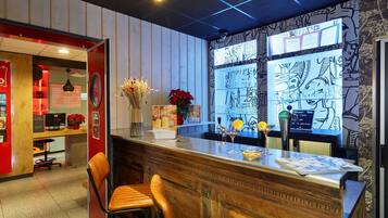 Zona de bar con mostrador de madera, taburetes y un jarrón decorativo con flores.
