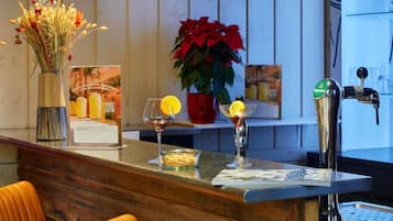 Un coin bar avec un robinet à bière, un verre de vin et une plante en pot.