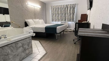 Une chambre d’hôtel moderne dotée d’un grand lit, d’un coin salon séparé, d’une salle de bain avec baignoire et d’un bureau avec une chaise.