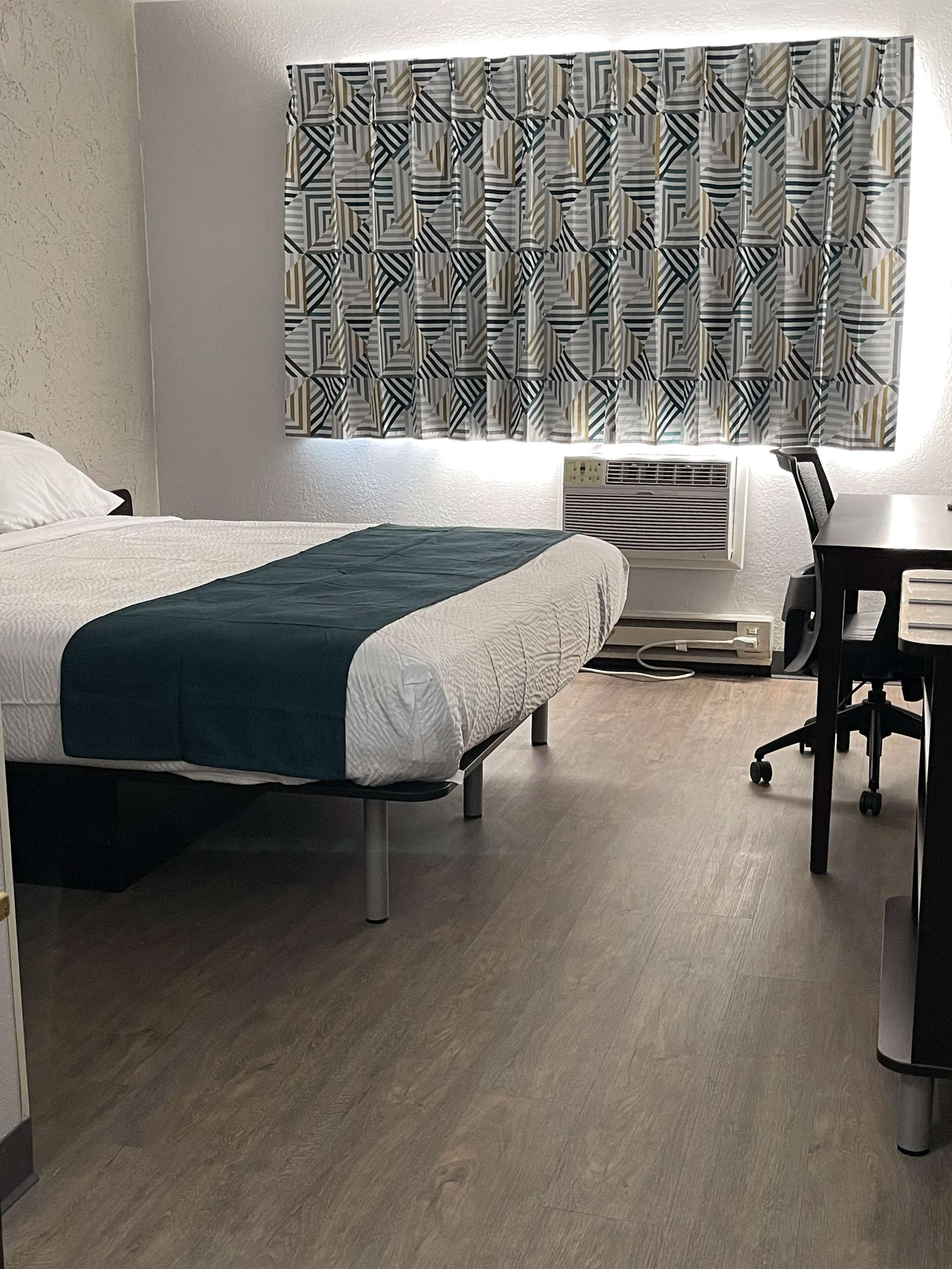 Habitación de hotel con dos camas, un escritorio y un aire acondicionado.