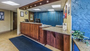 A reception desk with a wooden finish, a clock, and a bulletin board.