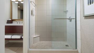 A modern bathroom with a glass-enclosed shower, a vanity with a mirror, and a towel rack.