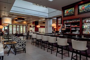 Zona de bar moderna amb sostres alts, tamborets i una àmplia selecció de licors.