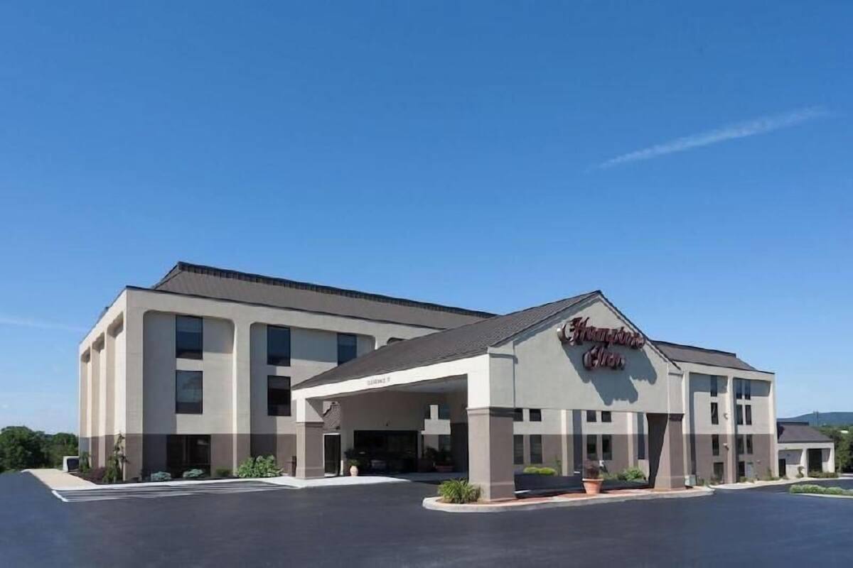 A modern hotel with a covered entrance, a flat roof, and a parking lot.