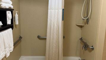 Un espace douche équipé d’une baignoire, d’un rideau de douche blanc et d’un porte-serviettes avec des serviettes.