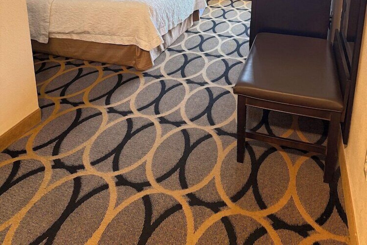 A hotel room with a bed, a desk, a chair, a TV, and a picture on the wall.