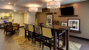 Une salle à manger d’hôtel avec une longue table, des chaises et un tapis à motifs.