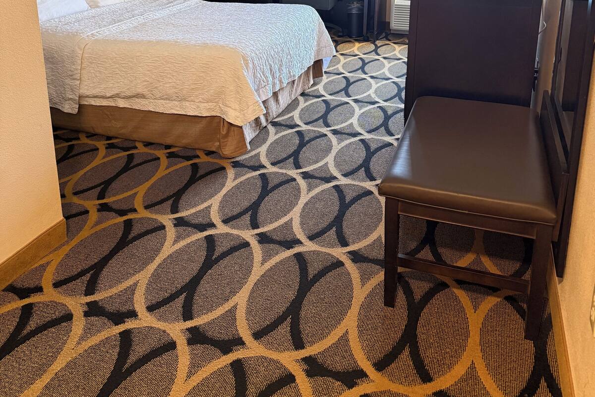 A hotel room with two beds, a desk, a chair, and a large window.