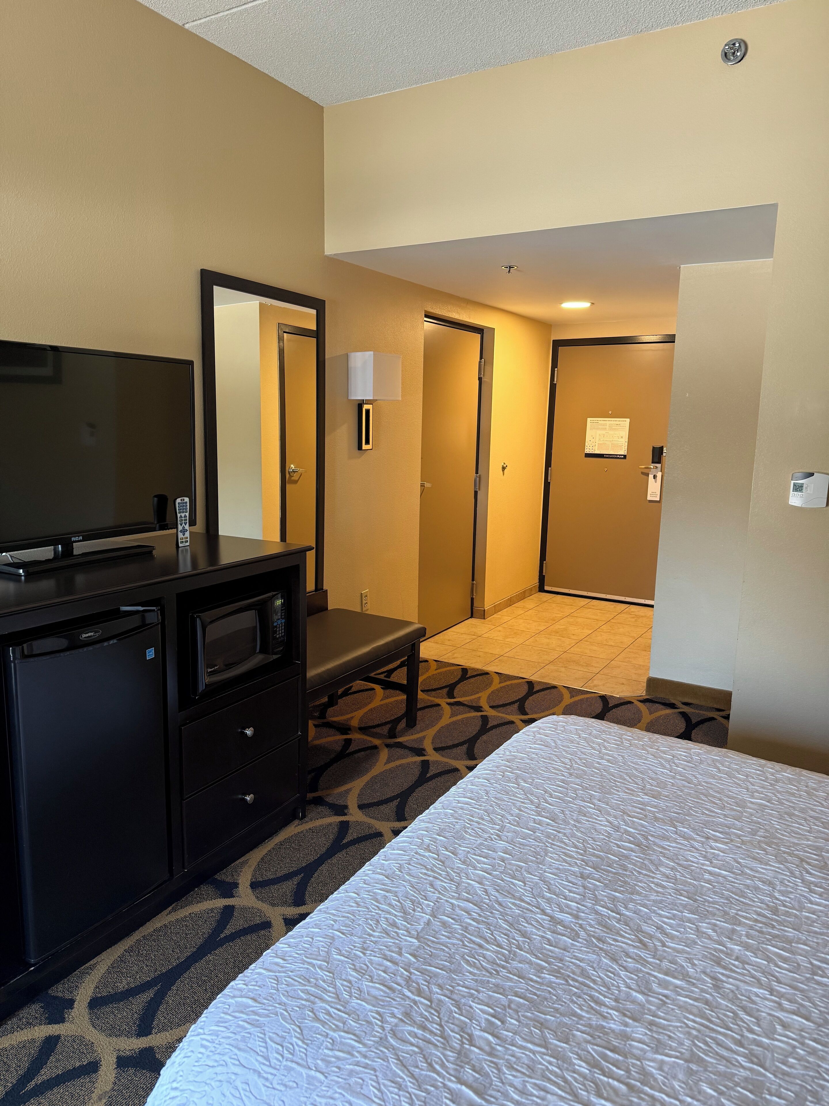 Una habitación de hotel con una cama, televisión, escritorio y microondas.