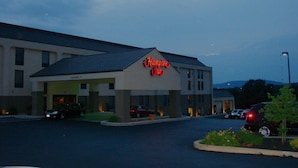 Un hôtel Hampton Inn avec un toit plat, un parking et quelques voitures garées devant.