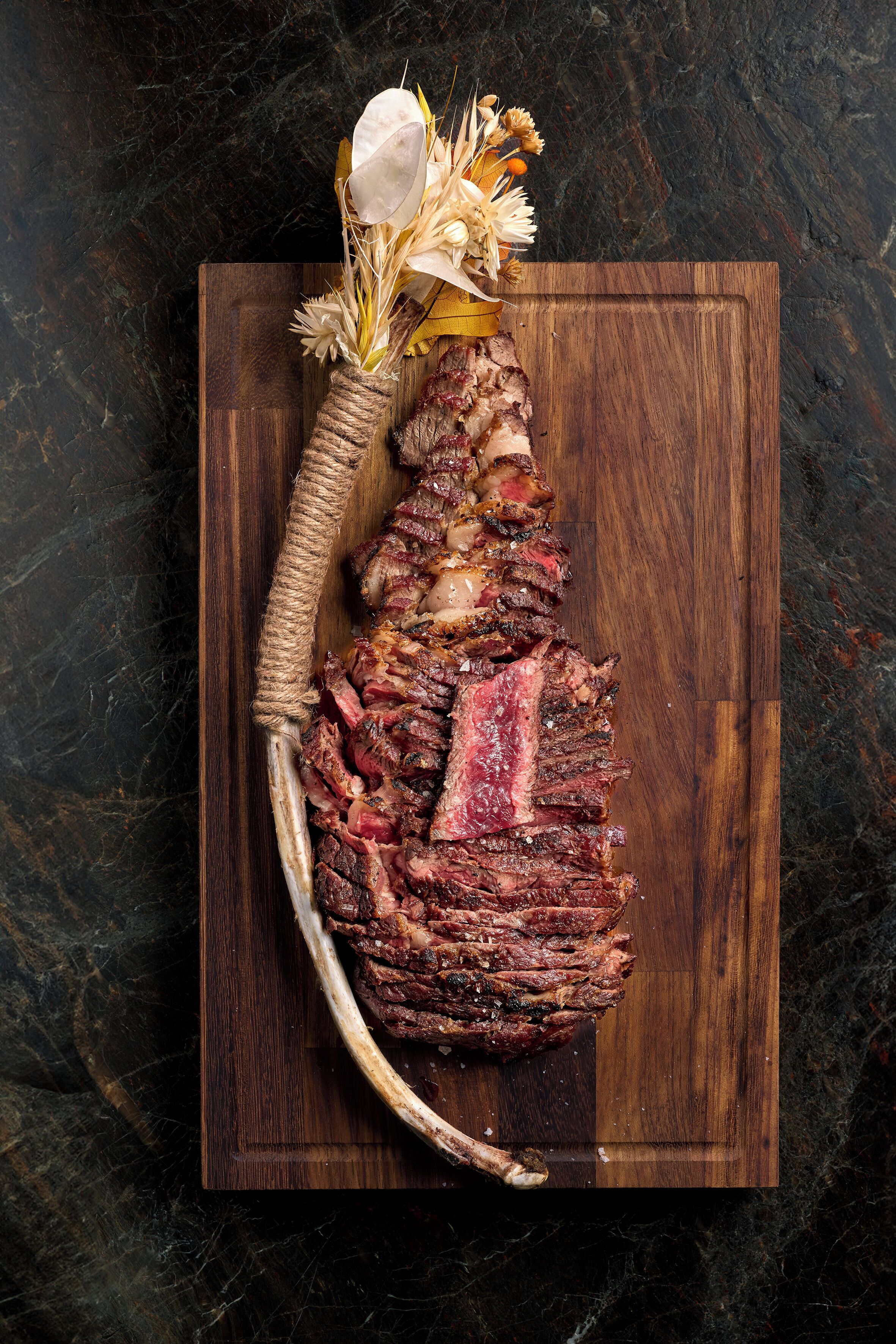 A steak with a decorative flower arrangement on a wooden board.
