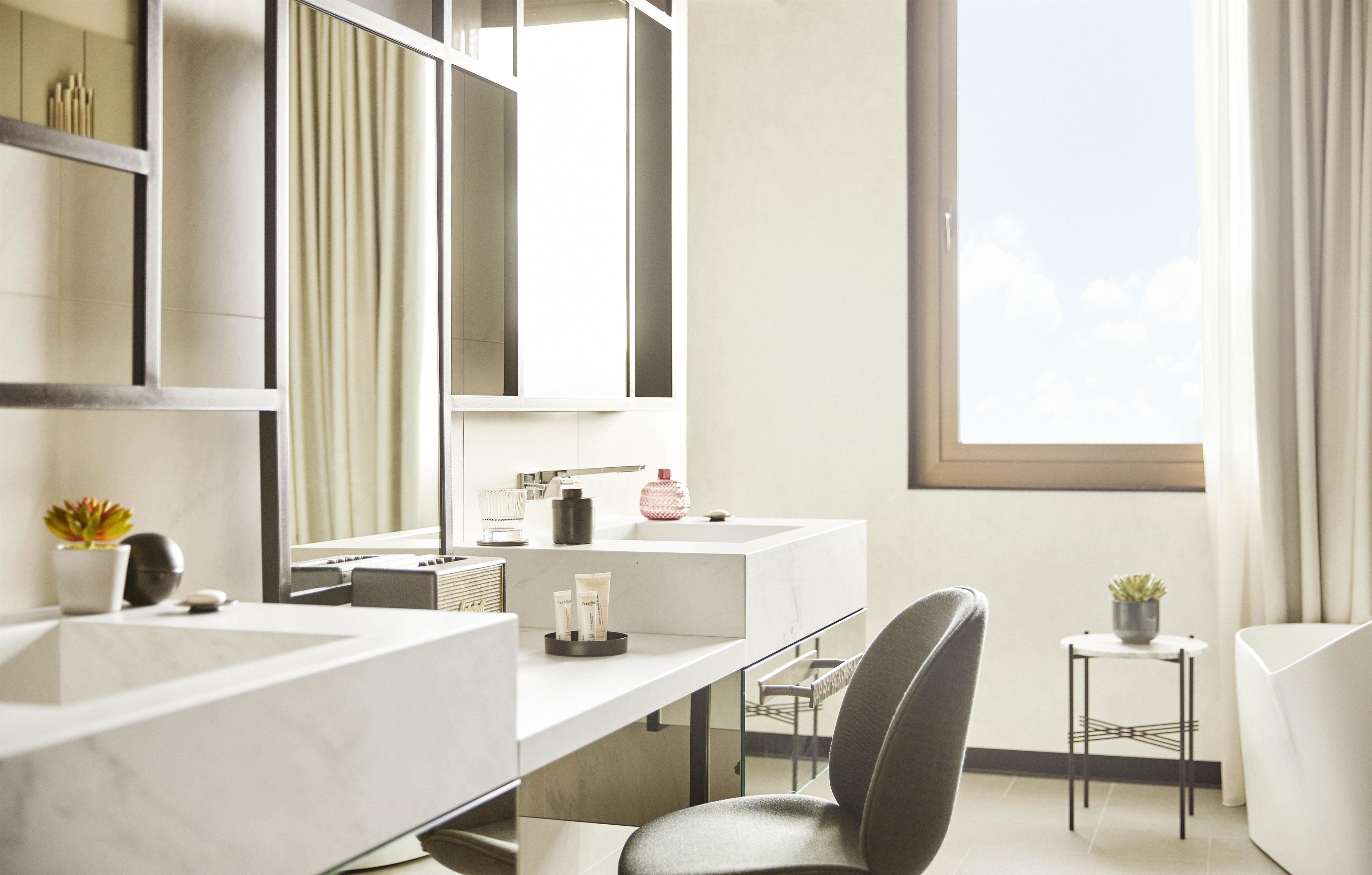 A modern bathroom with two sinks, a large mirror, and a window providing natural light.