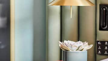 Een moderne kamer met een minimalistisch design, met een witte nachtkastje, een blauwe vaas met witte bloemen en een rood boek.