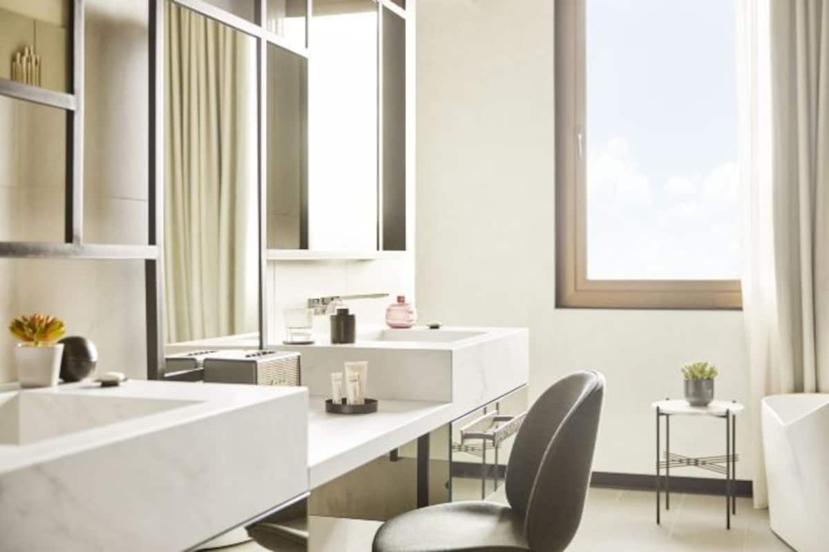 Une salle de bain moderne avec deux lavabos, un grand miroir et une fenêtre.