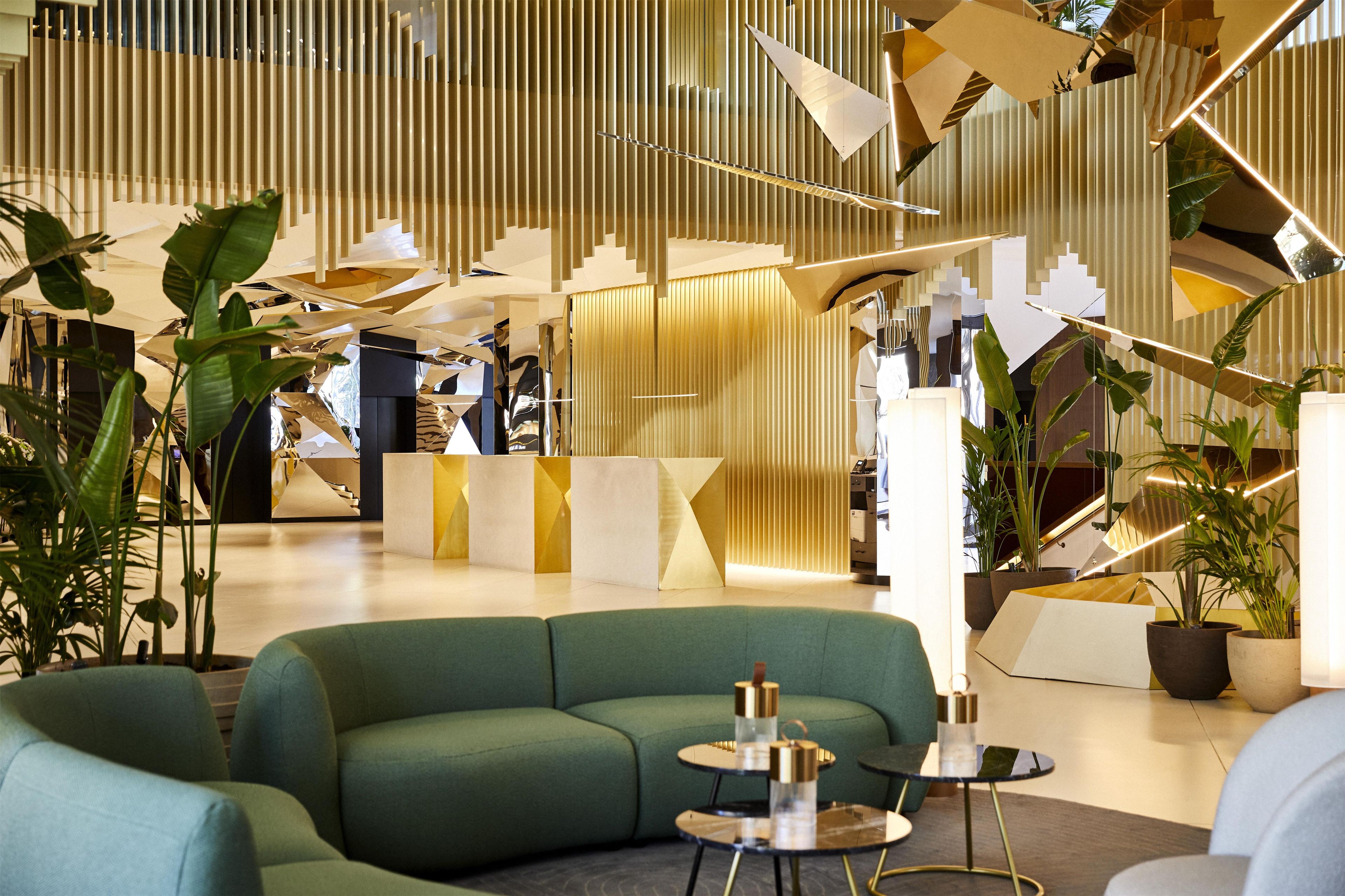Eine moderne Lobby mit einem grünen Sofa, einem Empfangstresen und einer Treppe.