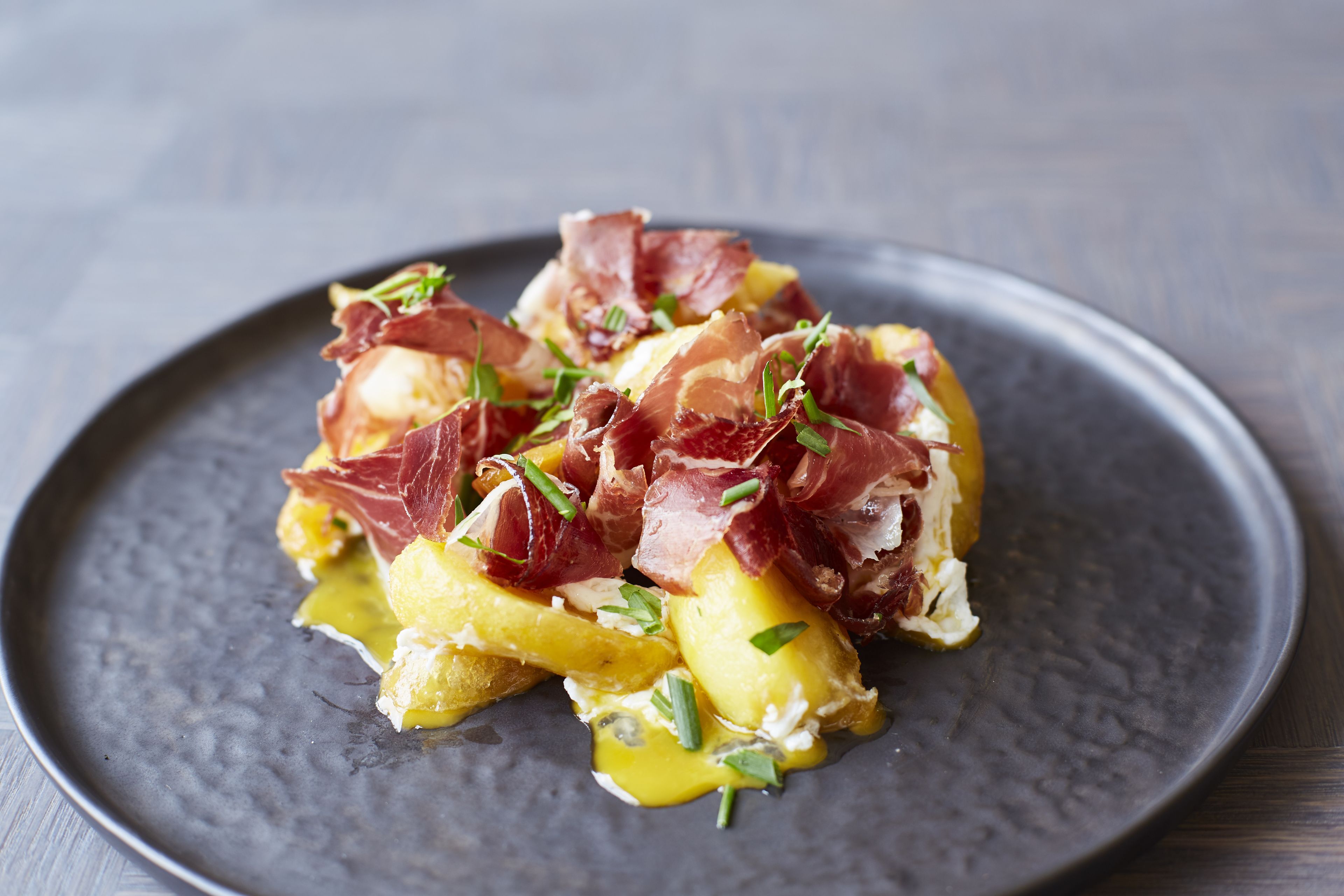 Un plato de comida con jamón serrano y cebollas verdes.