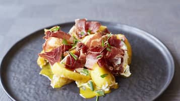 Un plato de comida con jamón serrano y cebollas verdes.