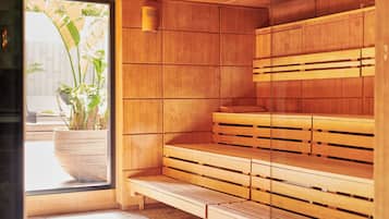 A sauna with wooden benches and a large potted plant by the entrance.