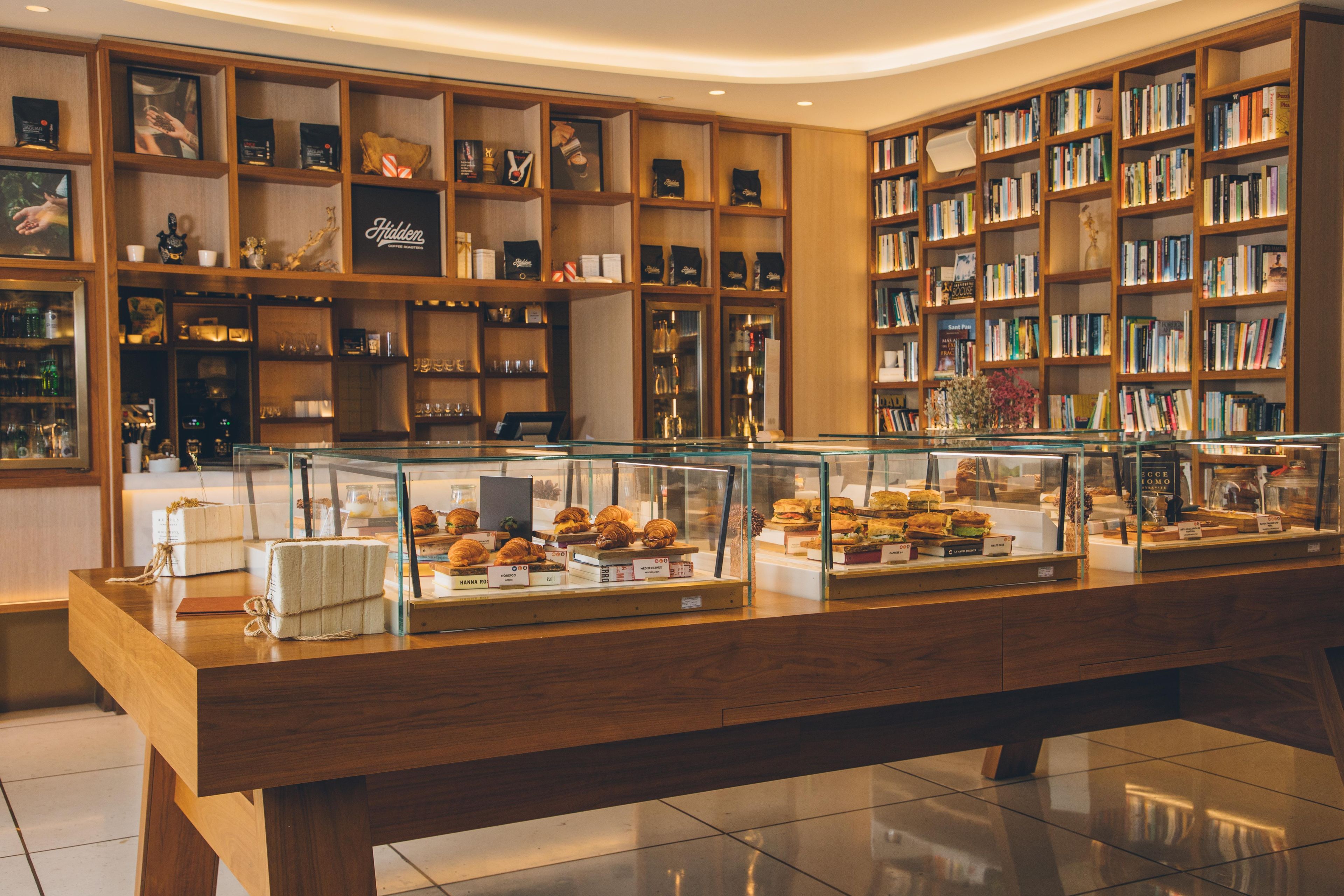 A bakery display with pastries and sandwiches, surrounded by bookshelves filled with books.
