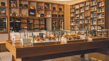 A bakery display with pastries and sandwiches, surrounded by bookshelves filled with books.