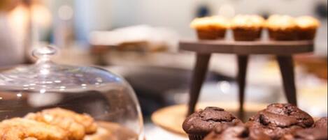 A dessert display with various pastries and muffins.