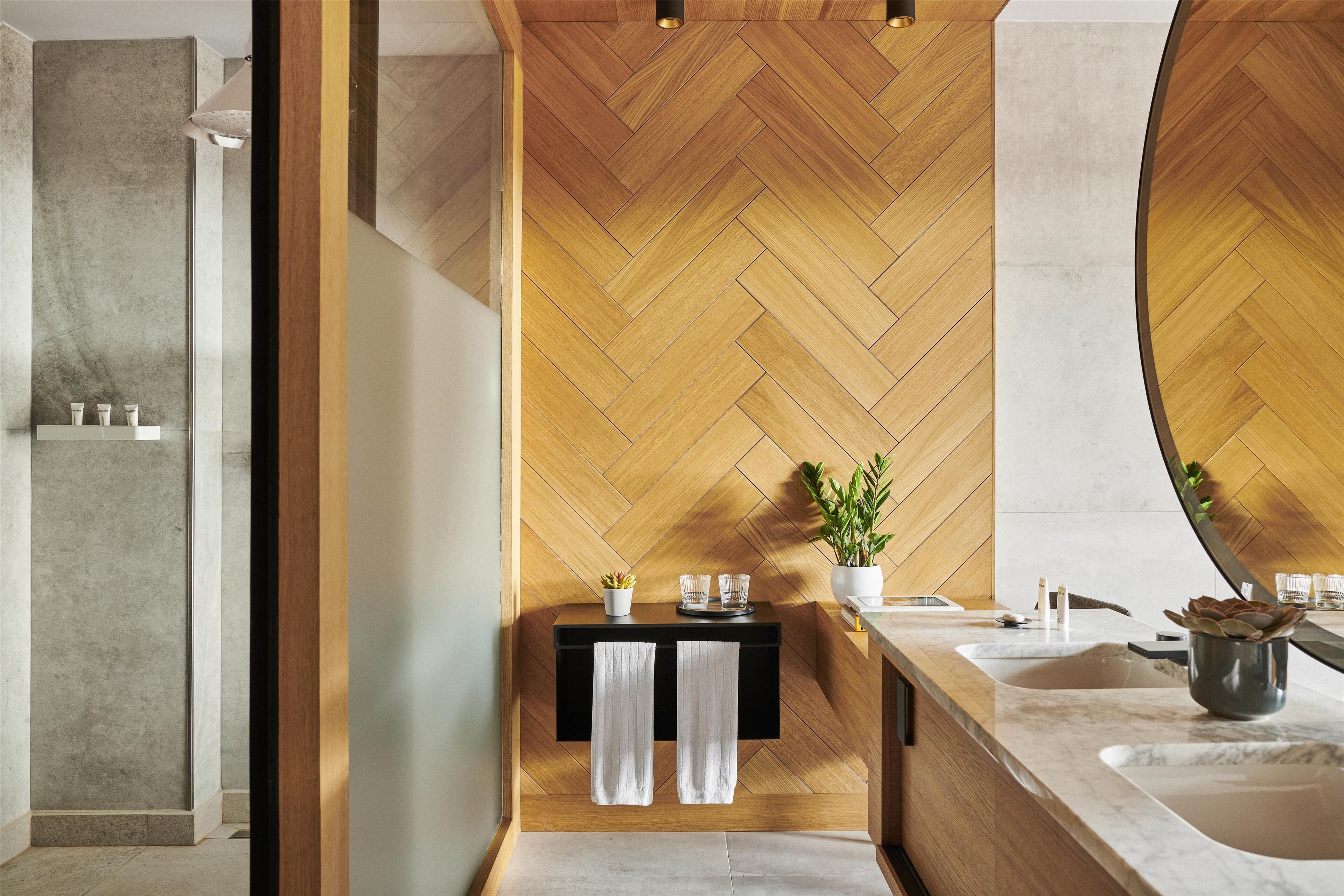 A modern bathroom with a herringbone wood wall, a black countertop, and a large mirror.