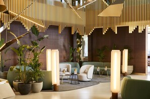 A modern interior with a staircase, seating area, and potted plants.
