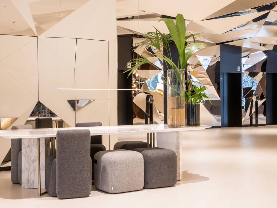 A modern interior with a marble table, grey upholstered chairs, and a potted plant.