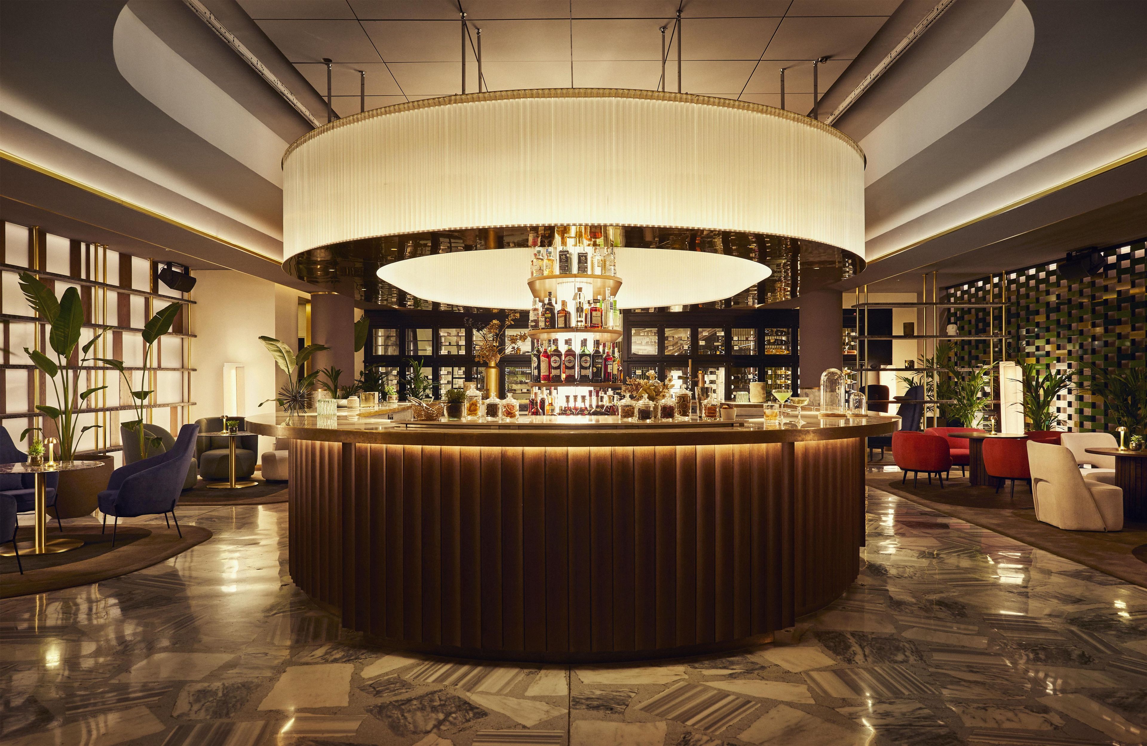 Eine Bar mit runder Bar, Sitzgelegenheiten und einer großen Chandelier.