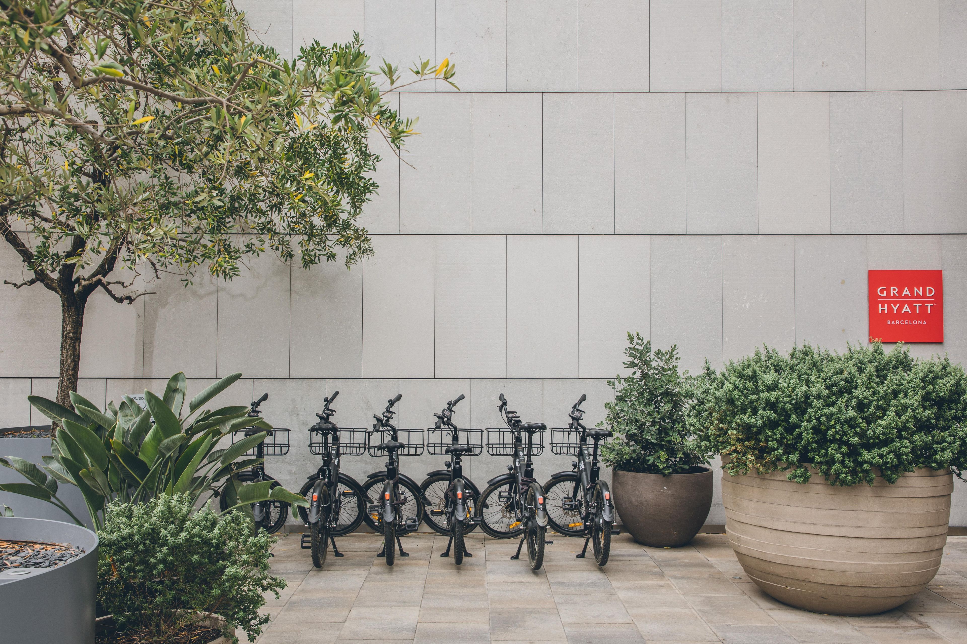 A row of bicycles parked against a wall with a sign reading 'Grand Hyatt Barcelona'.