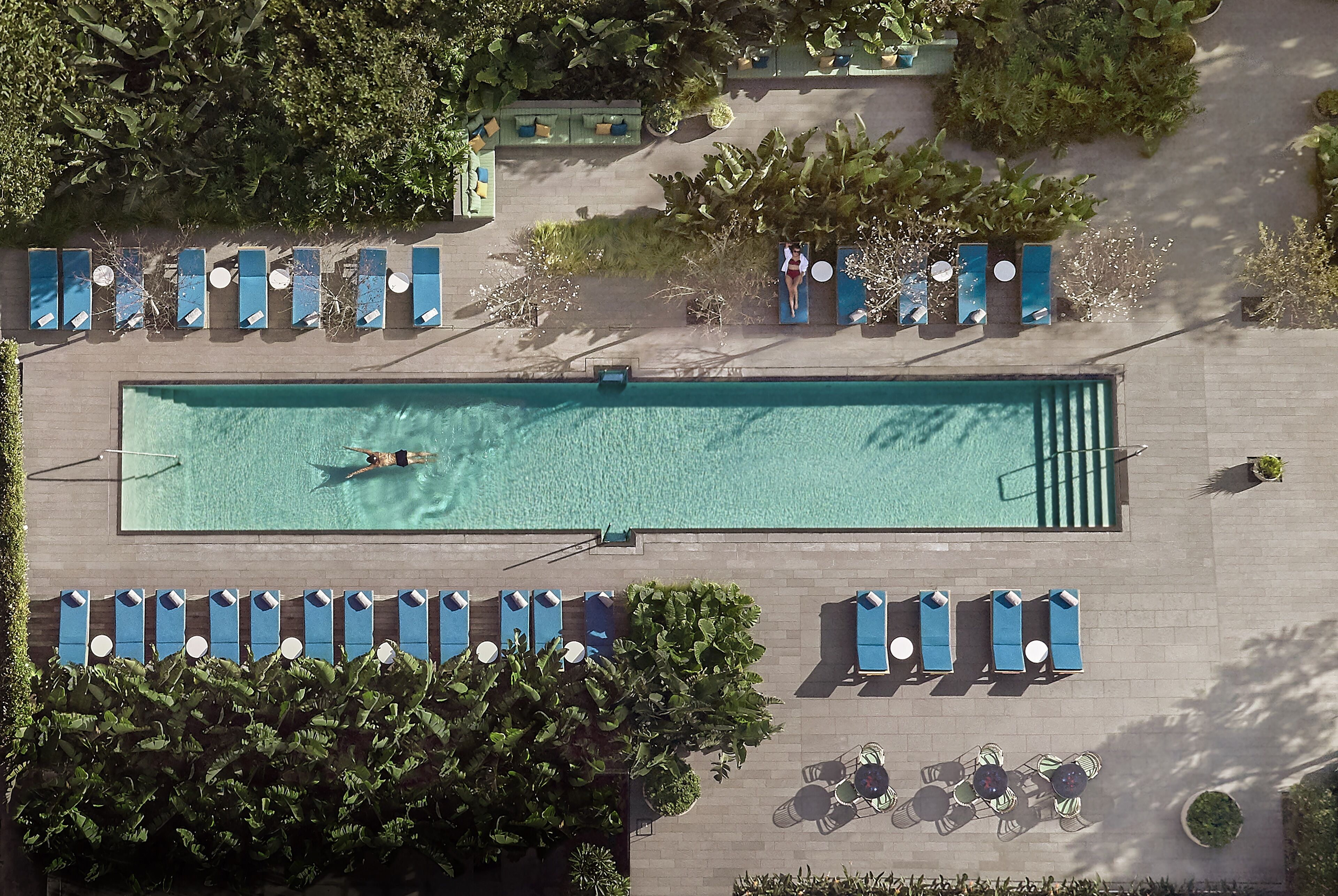 Vista aérea de uma área de piscina com espreguiçadeiras e uma mesa.