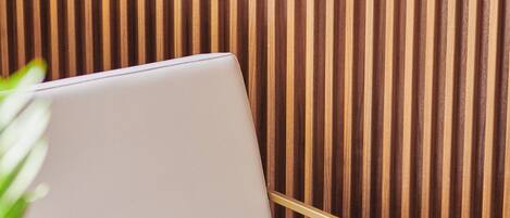 A modern room with a wooden slatted wall, a white chair, and a laptop on a wooden table.
