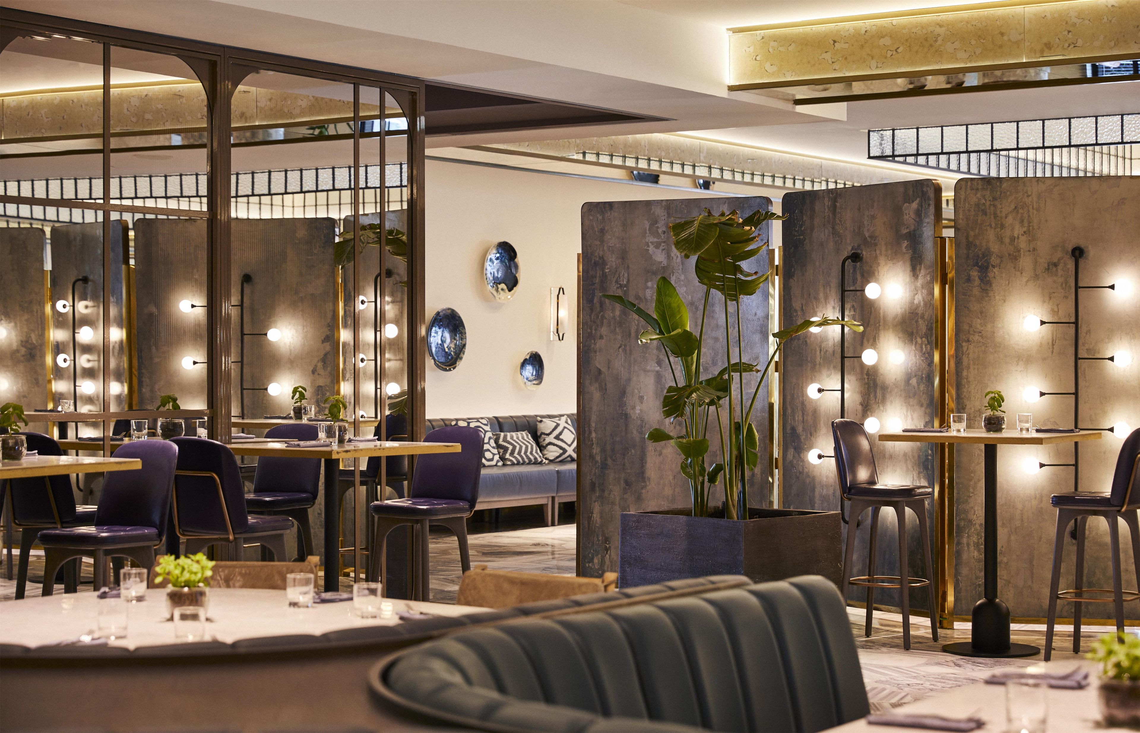 A modern restaurant interior with high tables, chairs, and decorative wall elements.