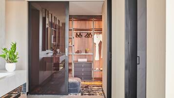 A modern hallway leading to a closet with a mirror, shelves, and a bench.